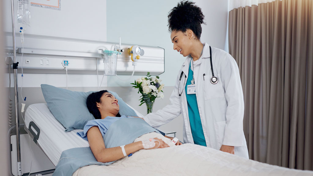 Patient senior effectuant ses premiers pas de rééducation avec l'aide d'une kinésithérapeute